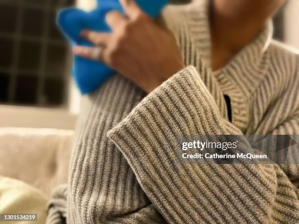 african-american woman holding heating pad to shoulder - heat pad stock pictures, royalty-free photos & images