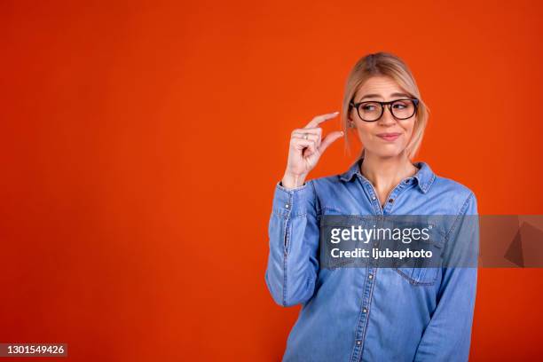 frustrated millennial woman demonstrating tiny measurement - length stock pictures, royalty-free photos & images