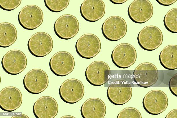 repeated lime slices on the yellow background - limone stock-fotos und bilder