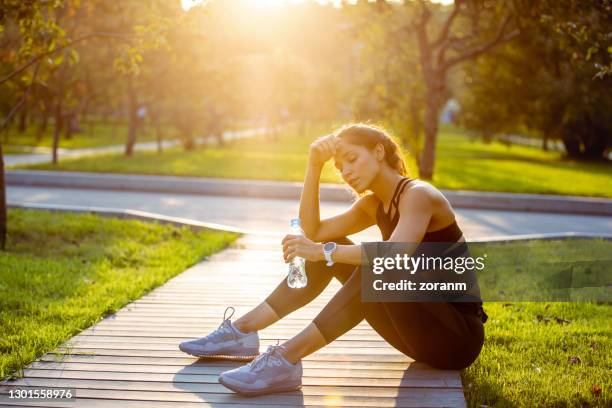 tired sportswoman resting after jogging - runner resting stock pictures, royalty-free photos & images