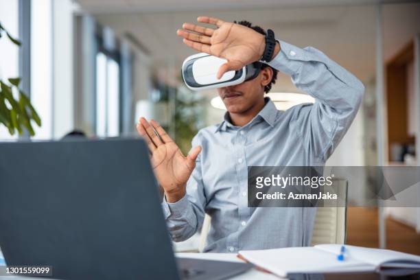 professionnel d’affaires interagissant avec un casque virtuel dans son bureau - casques réalité virtuelle photos et images de collection