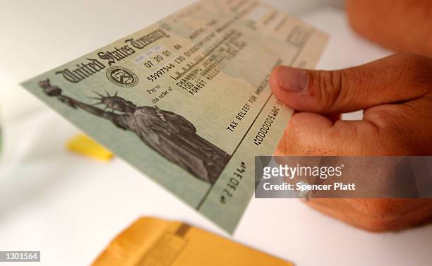 Tax payer looks at his rebate check July 25, 2001 in New York City. The U.S. Government is sending out 92 million tax rebate checks over 10 weeks as...