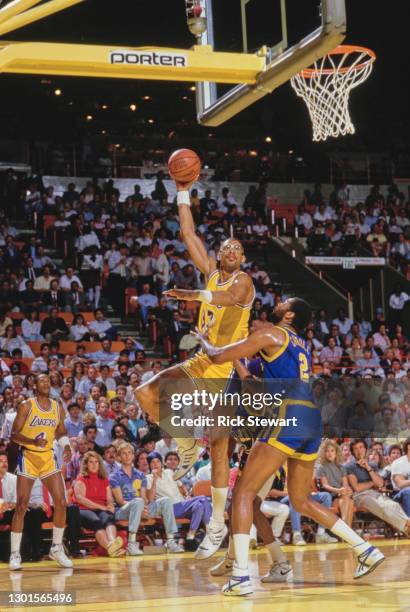 Kareem Abdul-Jabbar, Center for the Los Angeles Lakers jumps to make a single handed lay up shot to the basket over Joe Barry Carroll, Center for the...