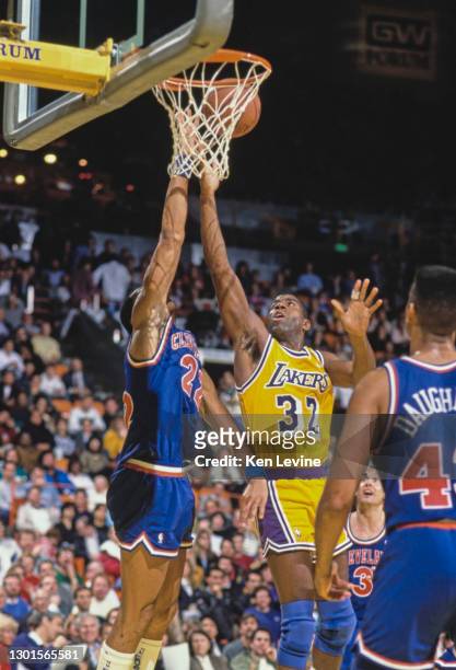 Earvin "Magic" Johnson, Shooting Guard and Power Forward for the Los Angeles Lakers jumps to make a lay up shot to the basket as Larry Nance of the...
