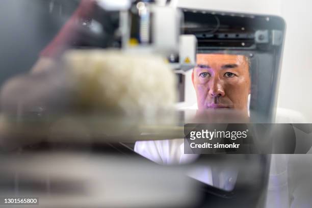 male biomedical engineer observing 3d model of brain in 3d printer - organe de reproduction masculin imagens e fotografias de stock