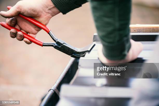 roofer builder worker finishing folding a metal sheet - bent stock pictures, royalty-free photos & images
