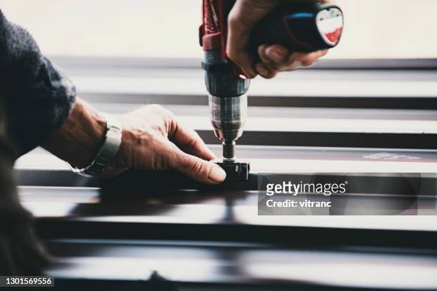 building contractor is installing metal roofing sheets - drill stock pictures, royalty-free photos & images