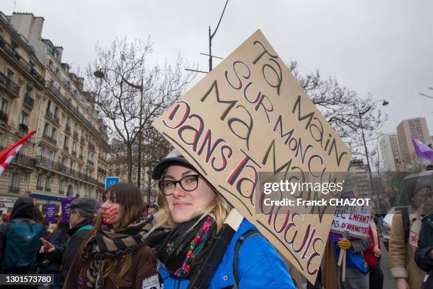 Femme portant une pancarte féministe "ta main sur mon cul, ma main dans ta gueule" lors de la manifestation pour la Journée Internationale pour les...