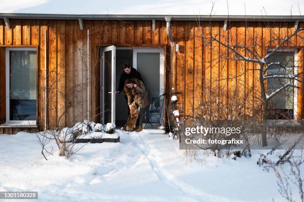 jovem casal com corgi ficar na frente da porta na neve de inverno - alo house winter - fotografias e filmes do acervo