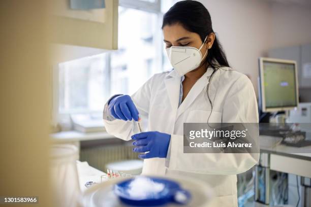 scientist in protective workwear working in laboratory - biochimiste photos et images de collection