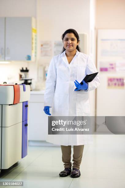 woman researcher standing in laboratory - female pharmacist with a digital tablet stock-fotos und bilder