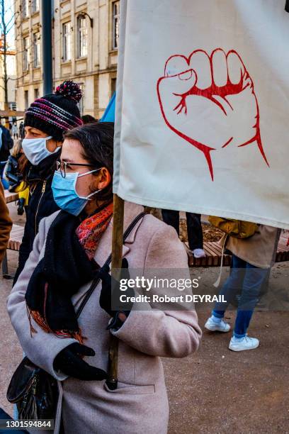 Une manifestante porte une banderole avec un poing fermé dessiné lors de la manifestation rassemblant 2000 étudiants et enseignants qui protestent...