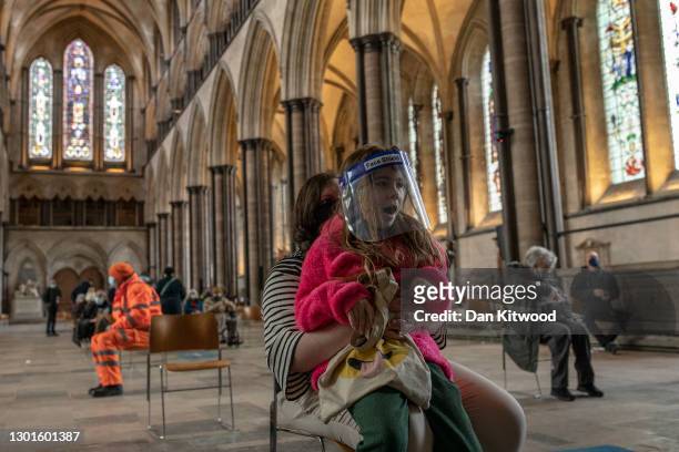 Mum Jade, waits with her daughter Lola after receiving her Covid-19 jab at a vaccination centre at Salisbury Cathedral on February 11, 2021 in...