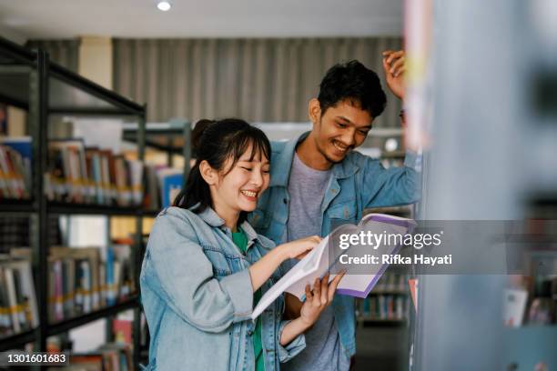 junges paar liest buch zusammen in der bibliothek - two men studying library stock-fotos und bilder