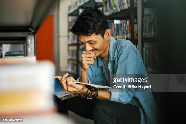 portrait of young man reading at library - indonesian ethnicity stock pictures, royalty-free photos & images