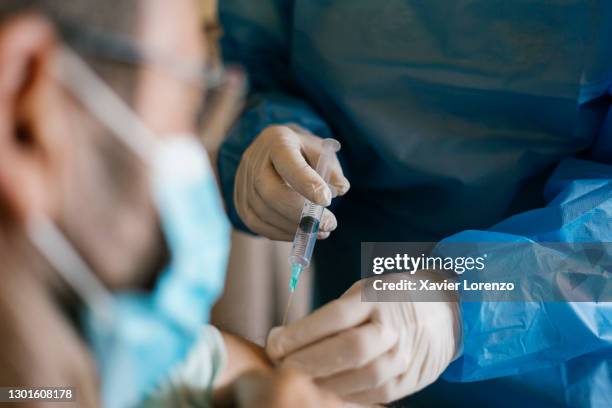 doctor injecting covid-19 vaccine to senior man at his home. - vaccination imagens e fotografias de stock