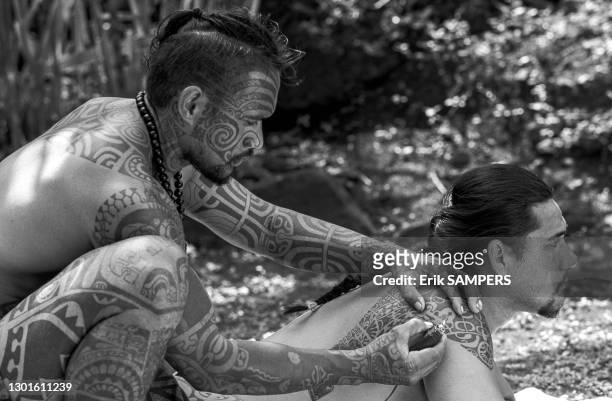 Homme tatoue un autre homme avec un tatouage traditionnel sur le corps, 24 juin 2002, Iles Marquises, Polynésie française.
