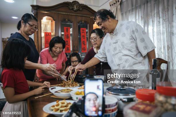 Family commence a reunion dinner on the eve of lunar new year by tossing "Yusheng" known as Prosperity Toss at home, while an immediate family from a...