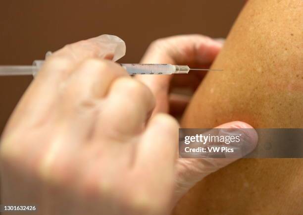 Syringe with vaccine being injects into person's arm, Covid-19 vaccinations, Pfizer and Moderna vaccines were issued FDA emergency use authorization...