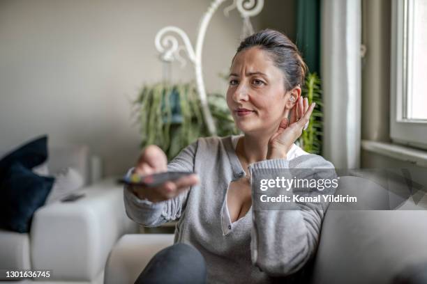 jeune femme adulte avec l’aide auditive regardant la télévision - problem photos et images de collection