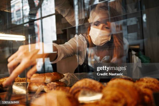 年輕女子在麵包店選擇糕點戴面罩 - 美味食品 個照片及圖片檔