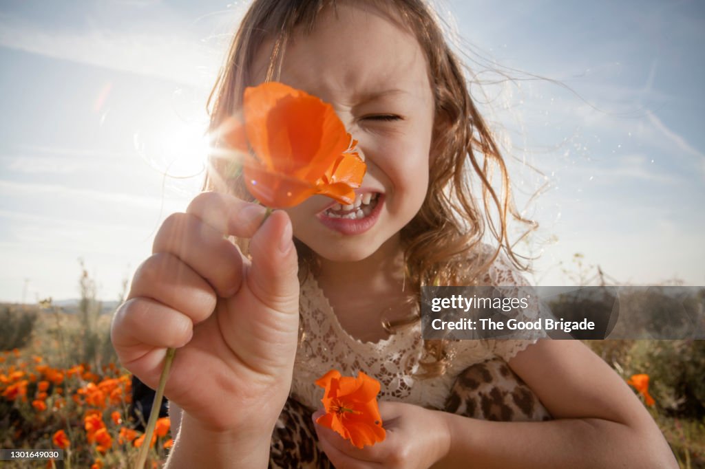 Girl holding orange poppy in front of face