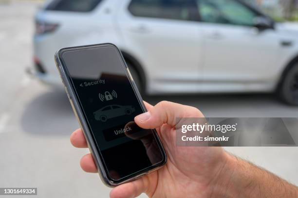 male hand using smart phone to lock car - stationery close up stock pictures, royalty-free photos & images