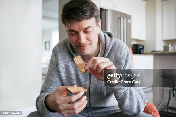 man snacks on chocolate and peanut butter wafers - waffel kuchen und süßwaren stock-fotos und bilder