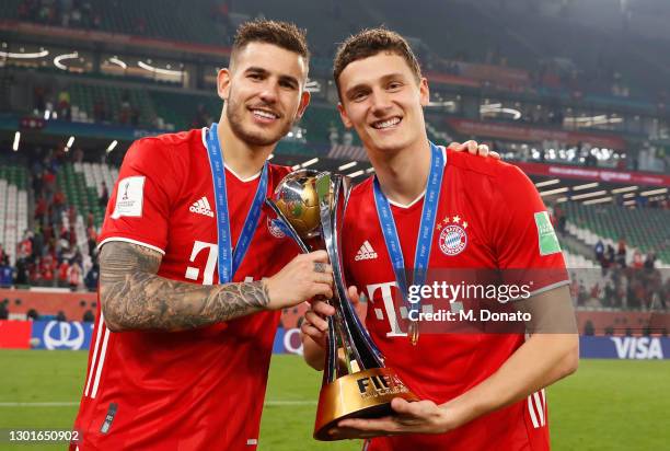 Benjamin Pavard of and Lucas Hernandez Muenchen pose with the trophy after winning the FIFA Club World Cup Qatar 2020 final between Bayern Muenchen...