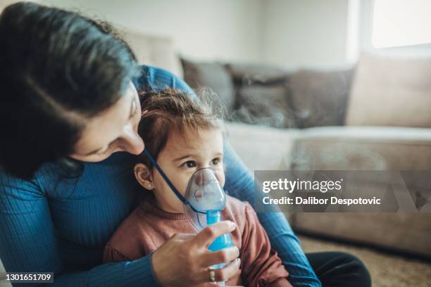 the woman and her daughter use an inhaler. - baby-cystic-fibrosis stock pictures, royalty-free photos & images