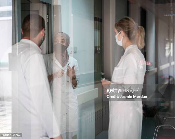 three doctors on hospital corridor having short meeting - doctor multiple exposure stock pictures, royalty-free photos & images