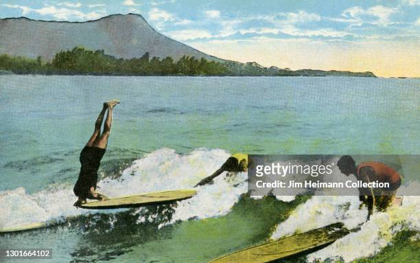 Souvenir postcard shows three men surfing at Waikiki. One of the men is doing a headstand on his surfboard, circa 1919.
