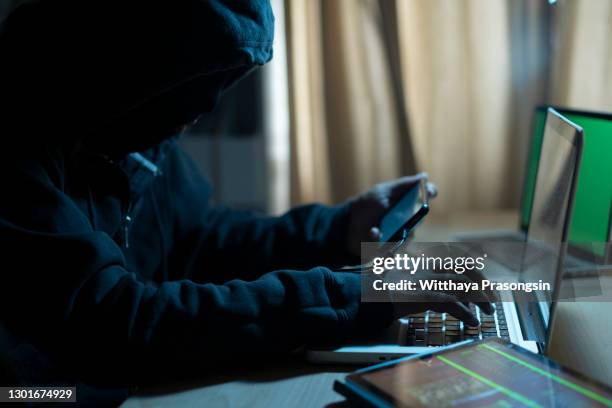 hacker dark face using laptop - android malware stock-fotos und bilder