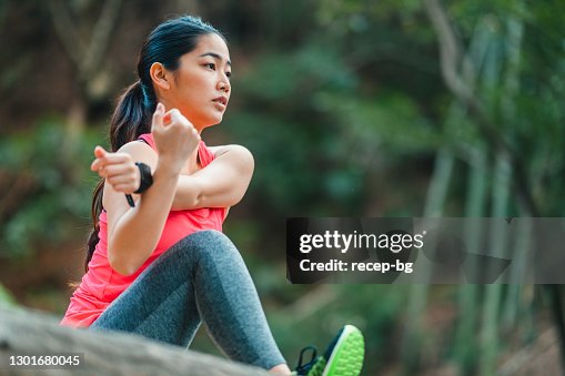 若い女性アスリートが腕と脚を伸ばし、スポーツトレーニングのためにウォーミングアップ 若い女性アスリートが腕と脚を伸ばし、スポーツトレーニングのためにウォーミングアップ