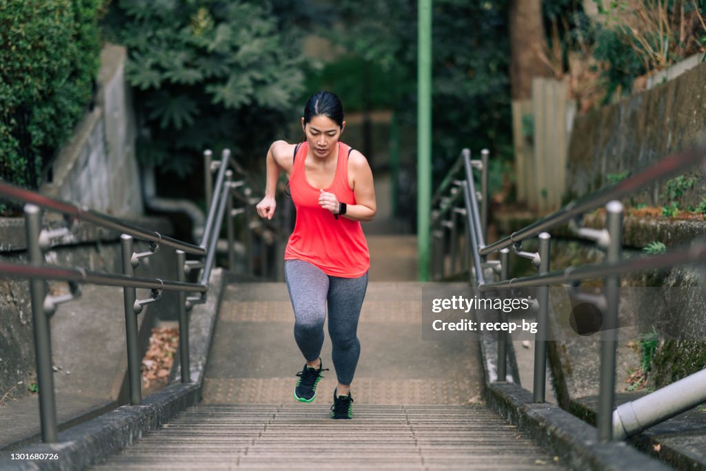 Young female athlete running up stairs