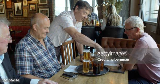 man bringing over a round of drinks in pub - english pub stock pictures, royalty-free photos & images