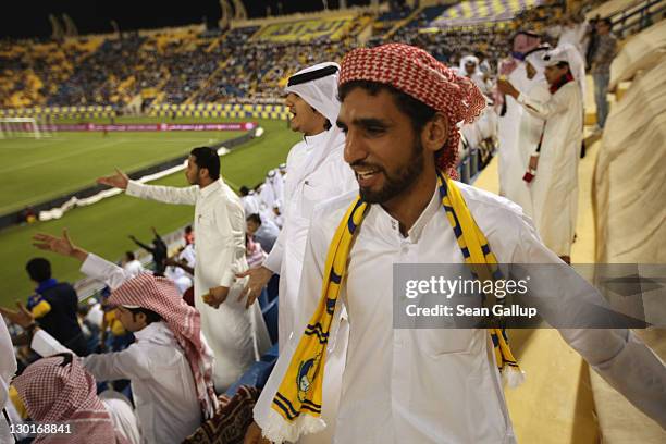 Fans wearing traditional local dress react to play during the Gharafa vs. Kharaitiyat Qatar Stars League football match at Al Gharafa Stadium on...