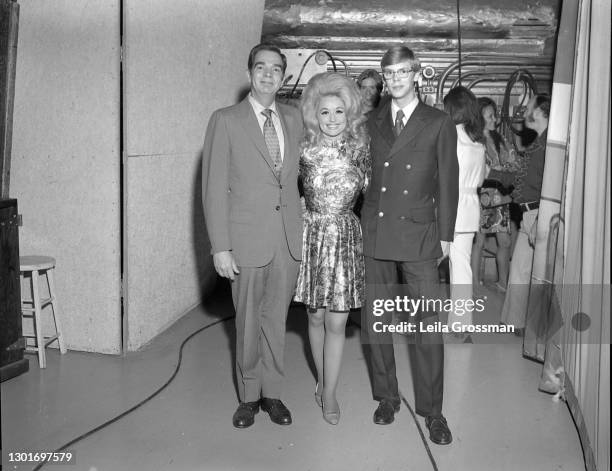 Country singer songwriter Dolly Parton poses for the camera with DJs backstage at the Grand Ole Opry circa 1970 in Nashville, Tennessee.