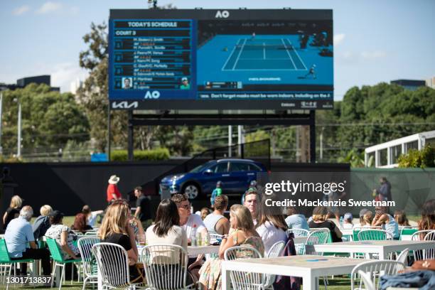 Attendees watch the big screens at Garden Square during day five of the 2021 Australian Open at Melbourne Park on February 12, 2021 in Melbourne,...