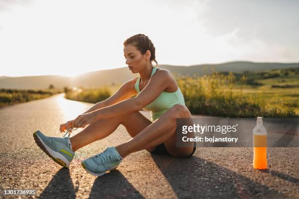 female runner tying her shoes preparing for a jog - desamarrado imagens e fotografias de stock