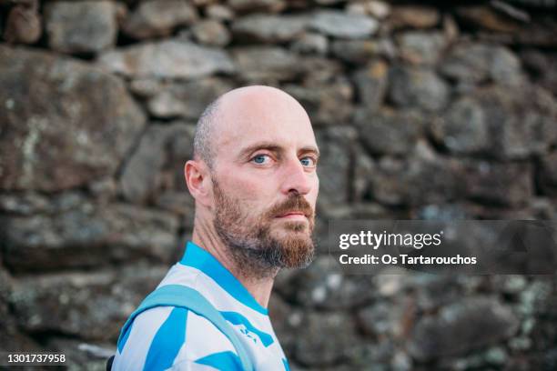 portrait of a man looking at camera with an old stone wall - steinwand stock-fotos und bilder