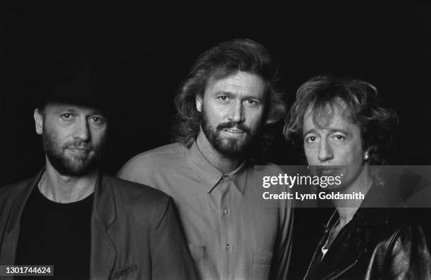 British pop group Bee Gees in a studio portrait against a dark background, location unspecified, January 1990.