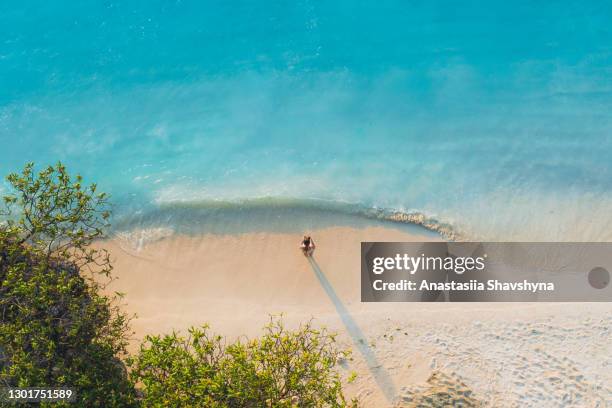 scenic aerial view of a woman staying at the white sand beach looking at the the pure turquoise waters of the ocean on zanzibar island, tanzania - white sand stock pictures, royalty-free photos & images