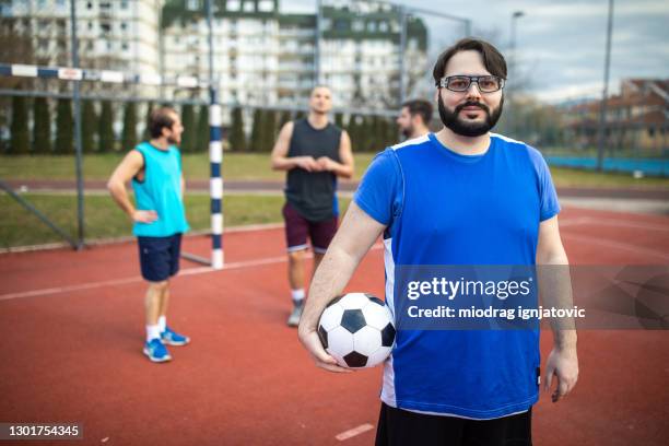 porträt eines übergewichtigen fußballers auf dem fußballplatz im freien - kräftig gebaut stock-fotos und bilder