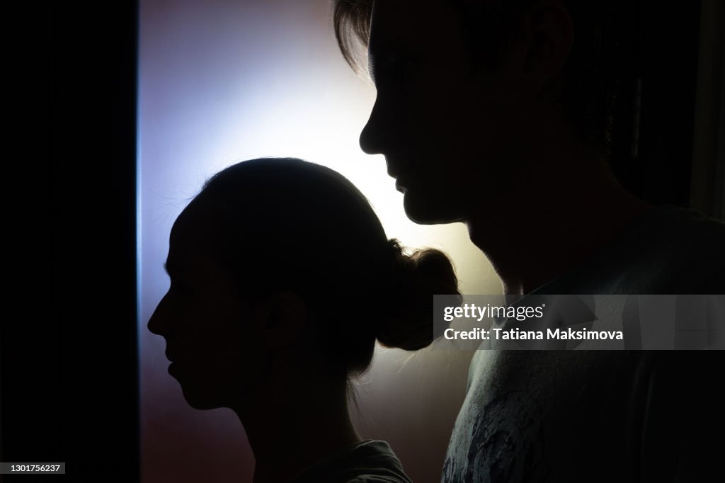 Silhouette of woman and man in the dark with blue light behind