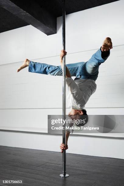 male pole dancer practicing in a pole dance studio - pole positie fotografías e imágenes de stock