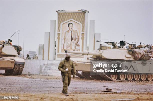 Military vehicles on the road with, in the distance, a mural of President of Iraq Saddam Hussein, near the 5th Mobile Army Surgical Hospital, during...