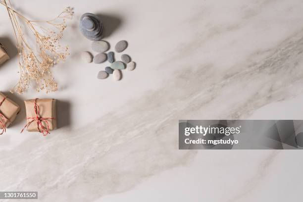 white zen balance stones and gift box on marble table, top view. - yule marble stock pictures, royalty-free photos & images