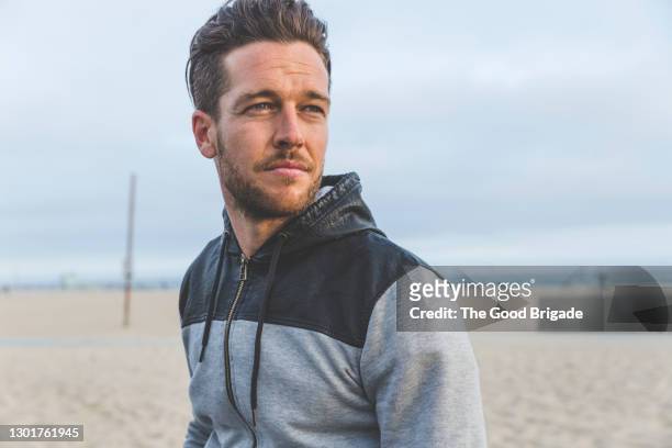 portrait of handsome man standing at beach - handsome people stock pictures, royalty-free photos & images