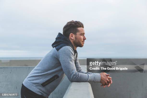 man leaning on wall looking out to sea - contemplation stock-fotos und bilder